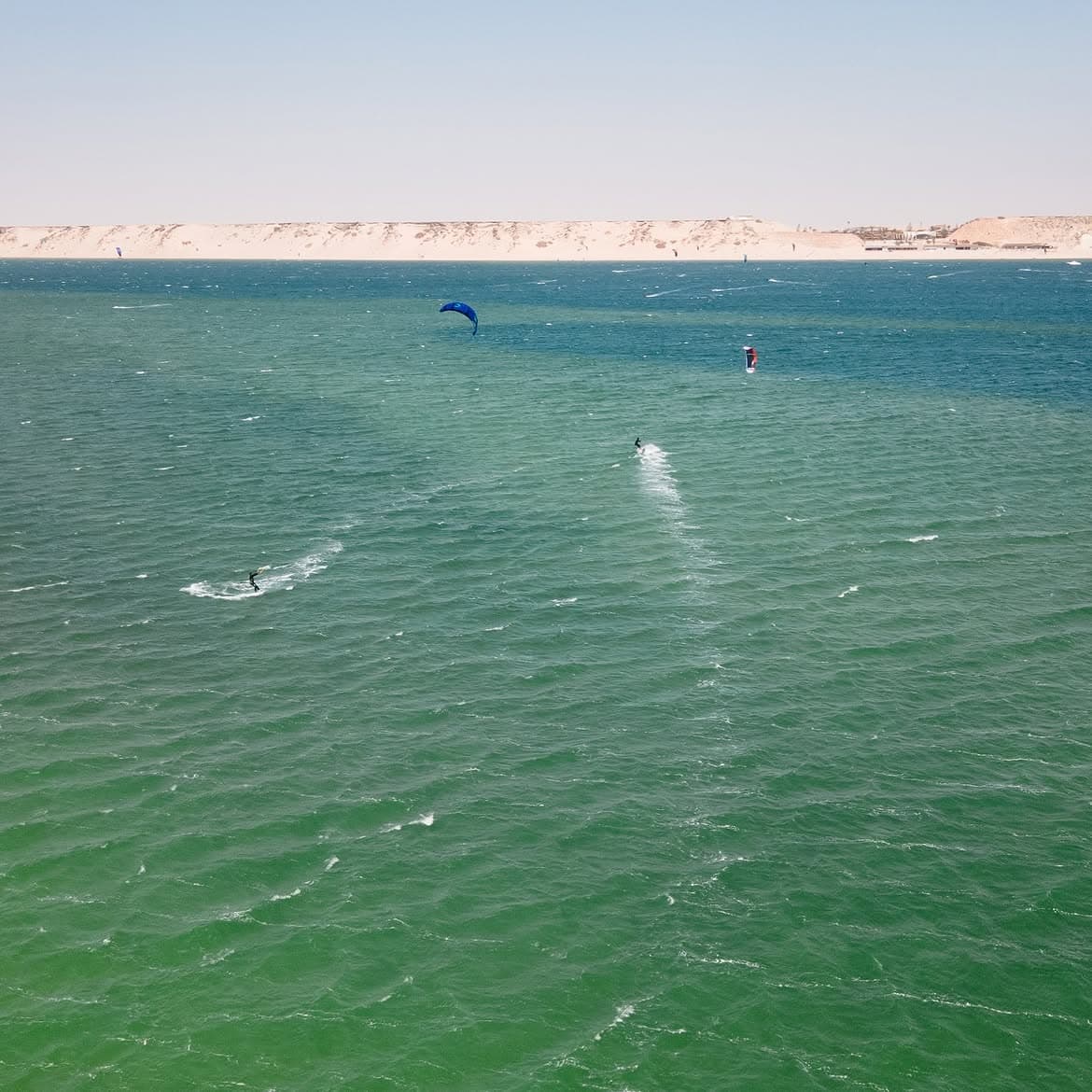 Riders naviguant sur les eaux turquoise du Main Lagoon face aux dunes de Dakhla