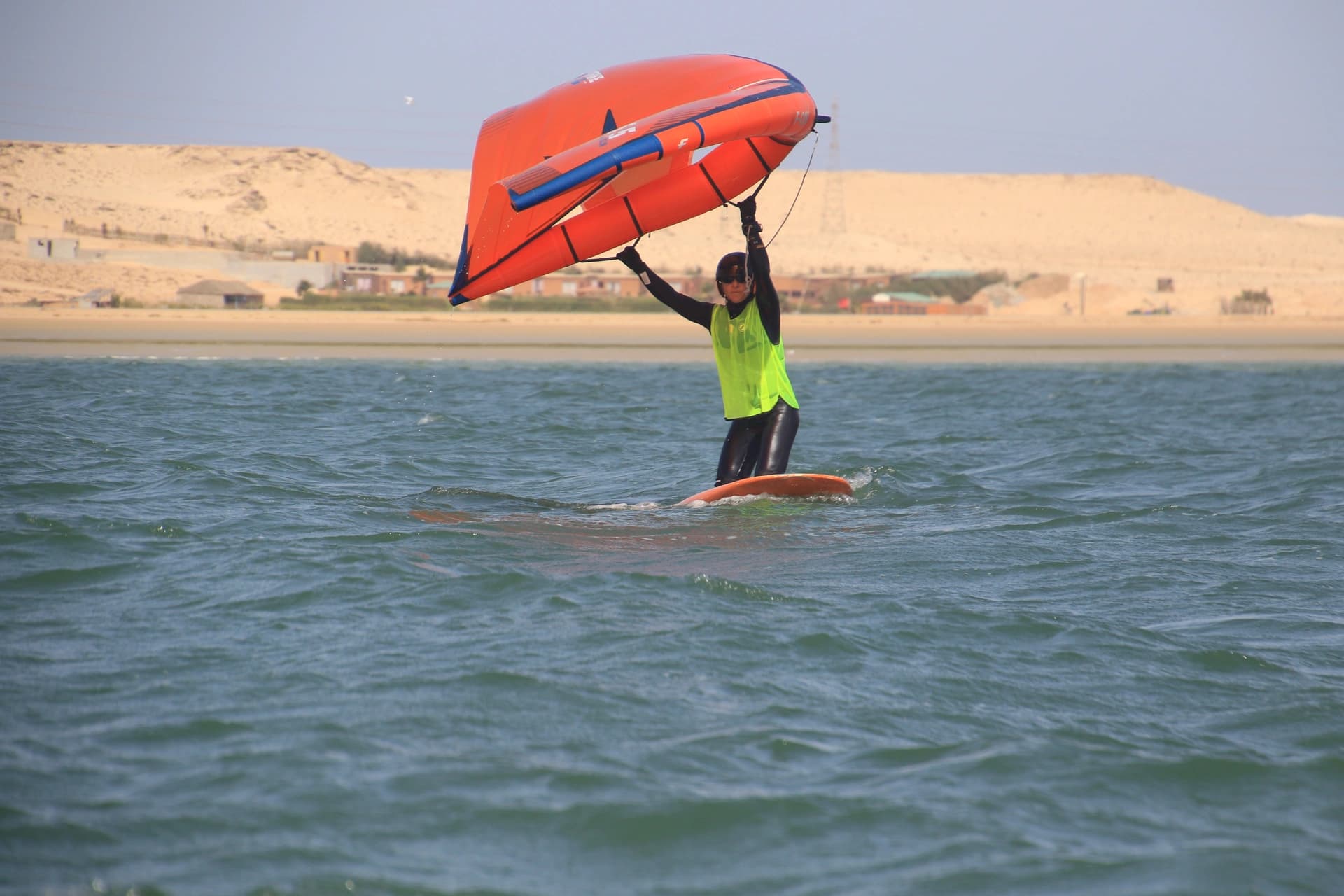 Élève à genoux sur sa planche contrôlant son aile de wingfoil dans le lagon de Dakhla