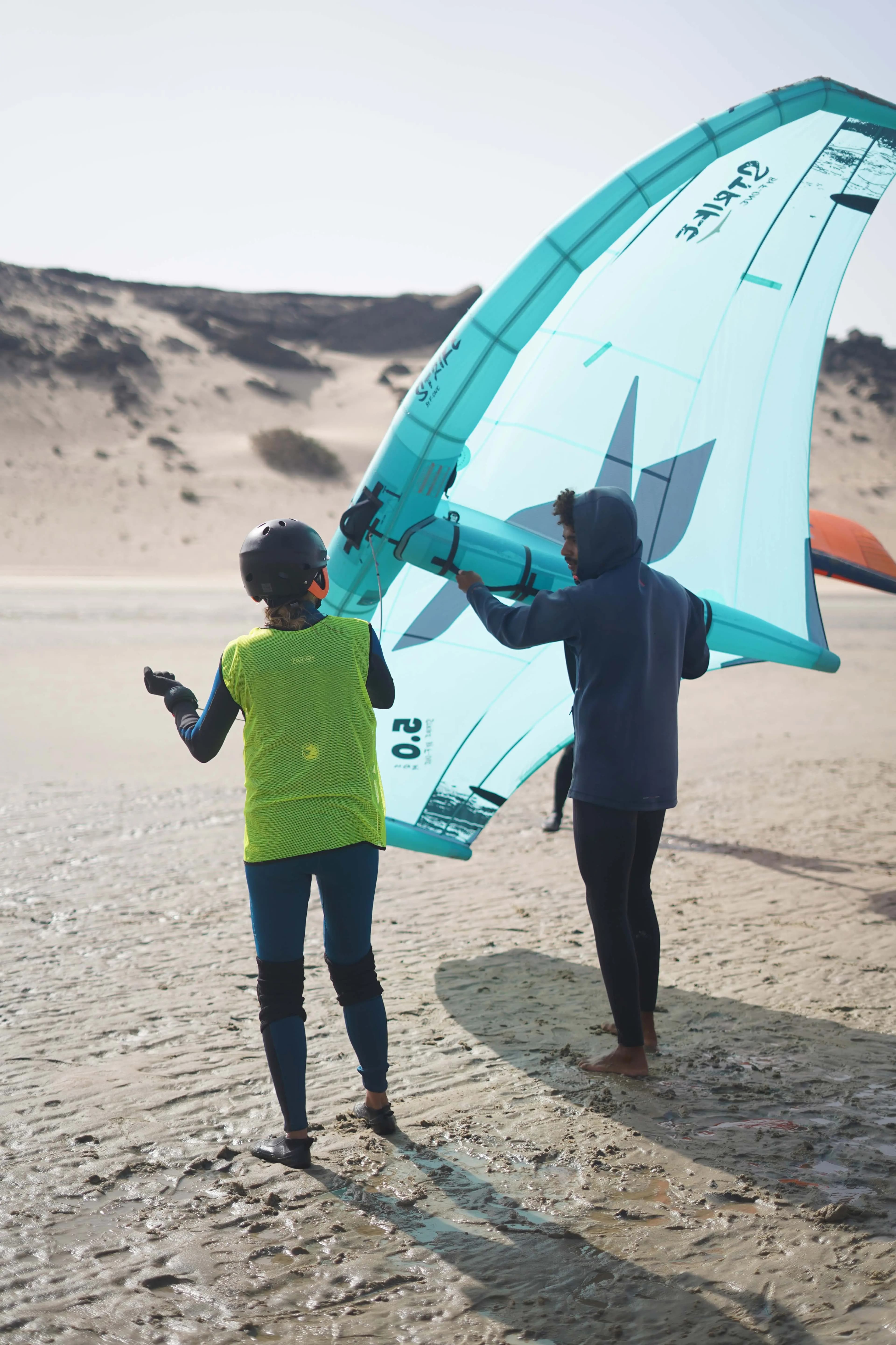 Moniteur accompagnant individuellement une élève dans la prise en main de son aile sur le lagon de Dakhla