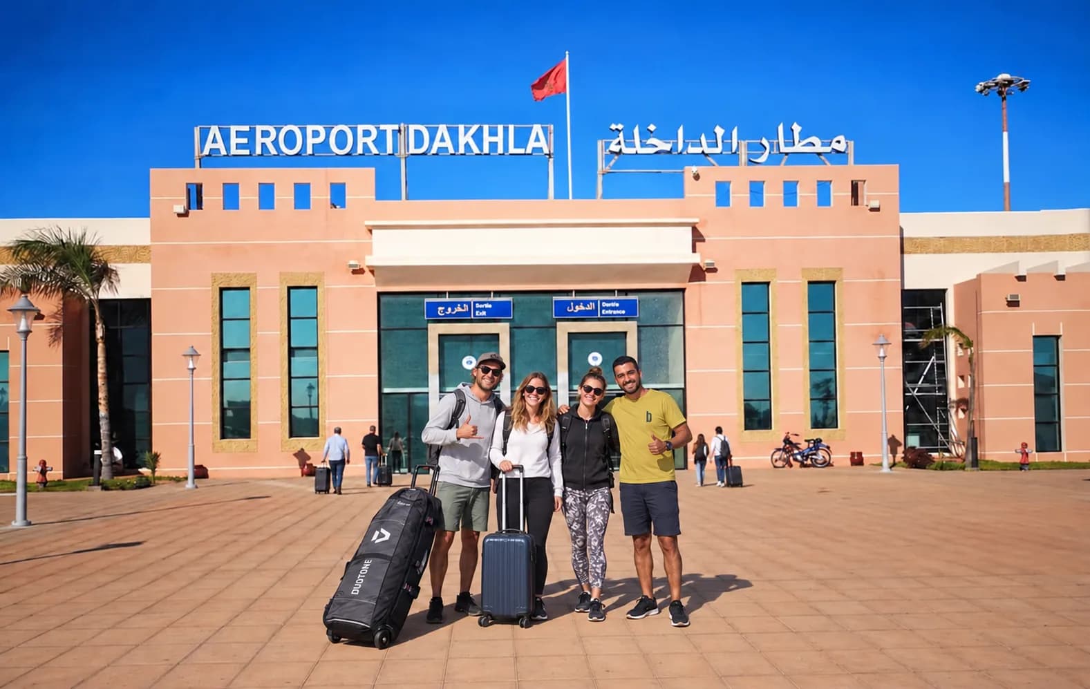 Membre de l’équipe Bluboarding accueillant des clients avec leurs bagages à l’aéroport de Dakhla